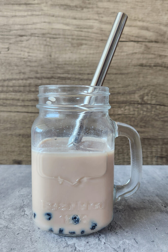 pale brown milk tea with boba in a mason mug with a metal straw